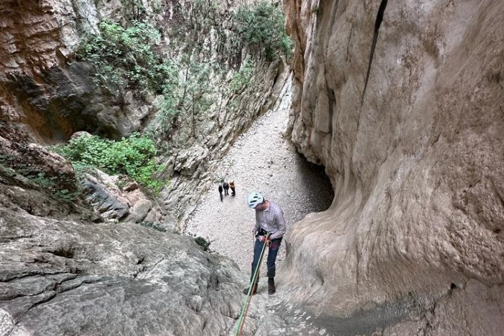 a man walking in front of a large rock