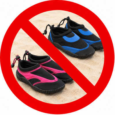 Two pairs of water shoes on sand, crossed out with a red prohibition symbol.