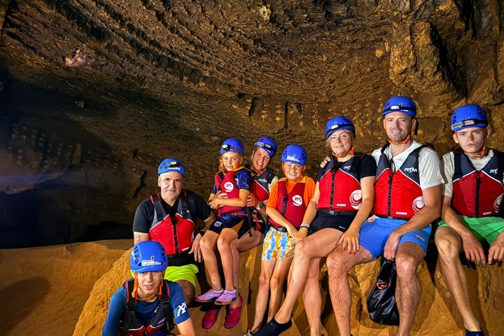 Group of people wearing helmets and life vests in a cave.