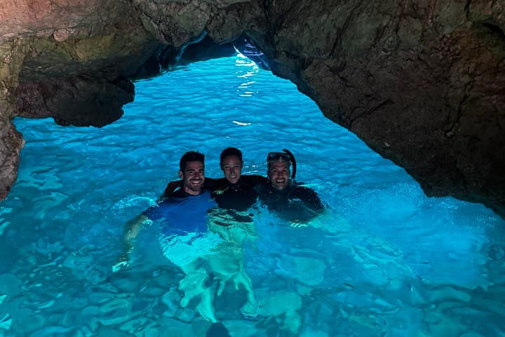 a person in a pool of water in front of a large rock