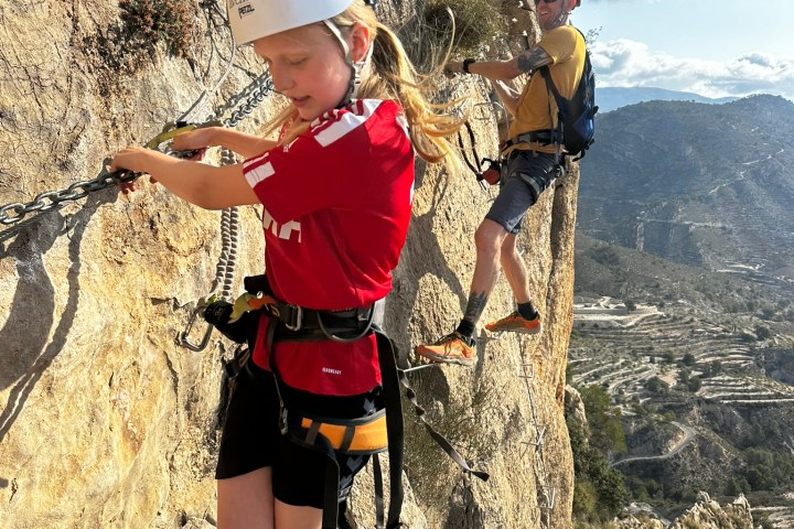 a young boy standing in front of a mountain