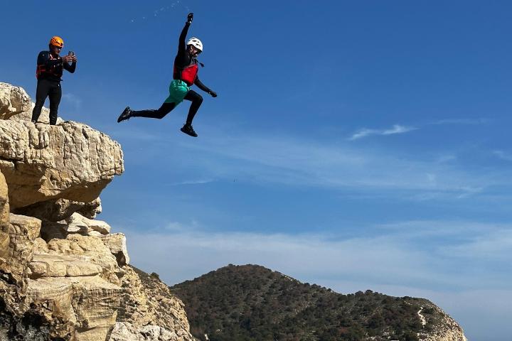 a man jumping in the air doing a trick on a rocky hill
