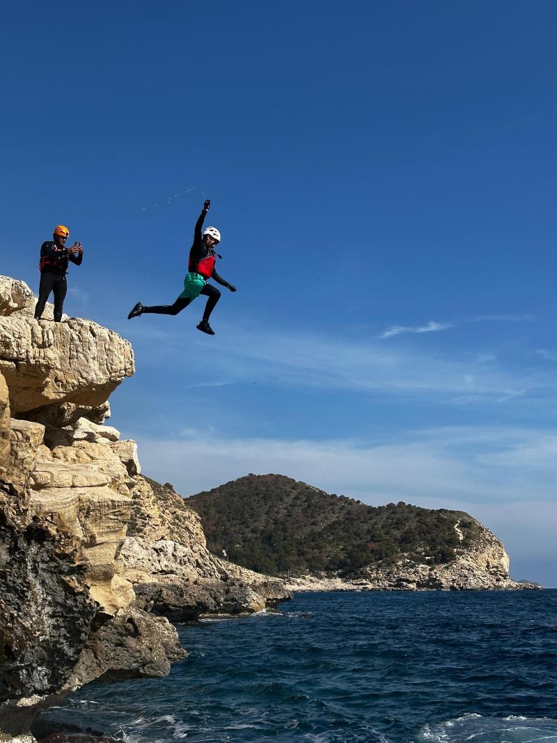 a man jumping in the air doing a trick on a rocky hill