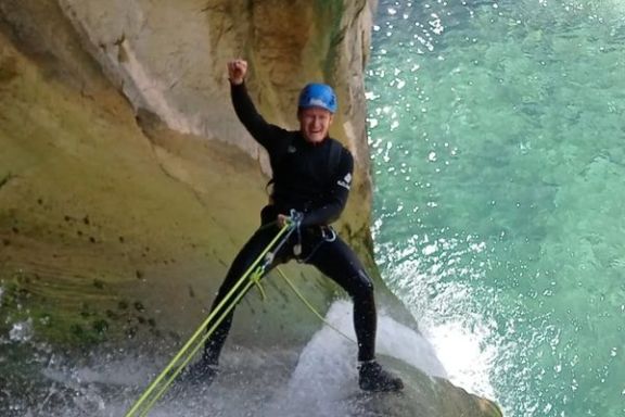Barranquista descendiendo en rápel junto a una cascada en Bolulla