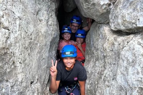 Grupo progresando por un paso estrecho durante la espeleología en Cova Fosca