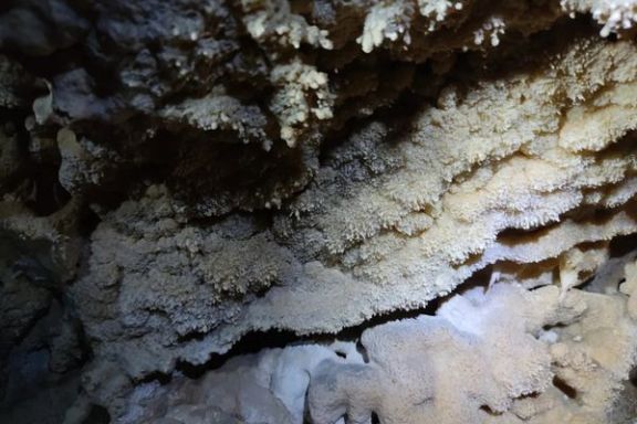 Formaciones minerales iluminadas en el interior de la Cova Fosca