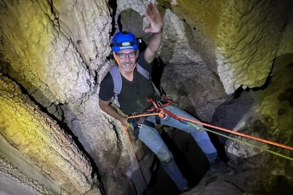 Participante realizando un rápel entre paredes estrechas de la Cova Fosca