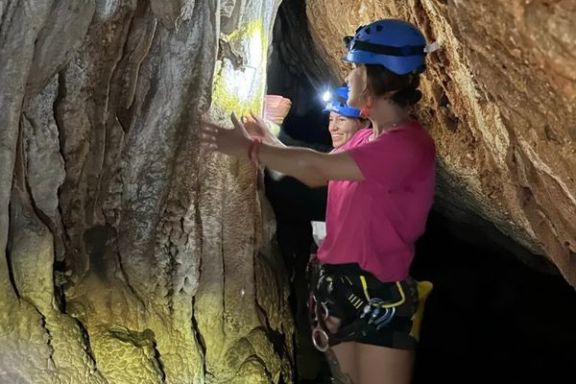 Participantes observando formaciones rocosas durante la espeleología en Cova Fosca