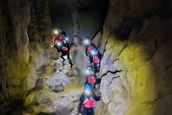 Grupo recorriendo las galerías de la Cova dels Coloms con frontal