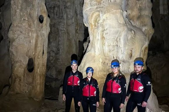 Participantes junto a una gran columna de roca en el interior de la Cova dels Coloms