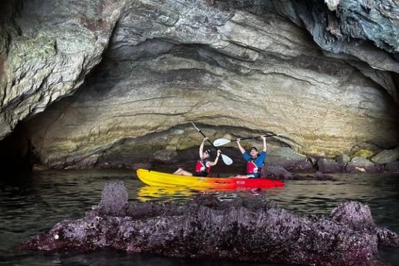 Pareja disfrutando de la ruta en kayak junto a una cueva marina en Jávea