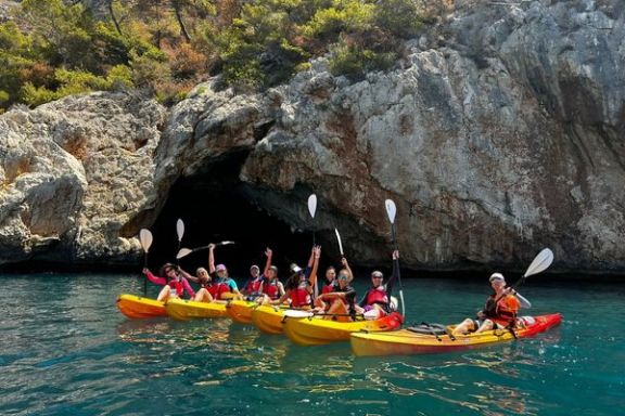 Grupo en kayak frente a una cueva marina durante la ruta por la Cala Granadella
