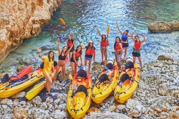 Grupo de participantes junto a los kayaks en la Cala Granadella antes de iniciar la ruta