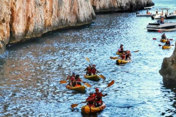 Grupo navegando en kayak por la Cala Granadella de Jávea entre los acantilados
