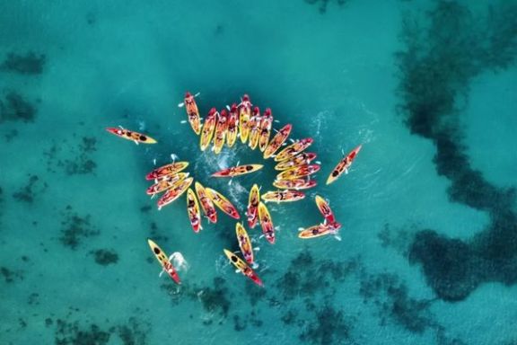 Vista aérea del grupo navegando en kayak sobre aguas cristalinas en Villajoyosa.