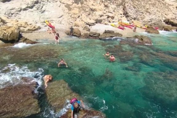 Participantes disfrutando del baño en una cala de aguas cristalinas durante la excursión en kayak.