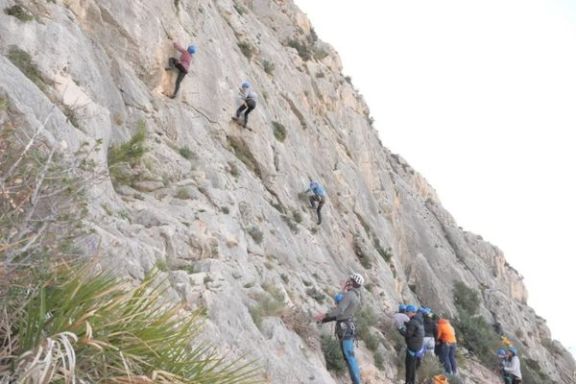 Grupo de participantes practicando escalada en una pared de roca del Morro de Toix, en la zona de Altea y Calpe.