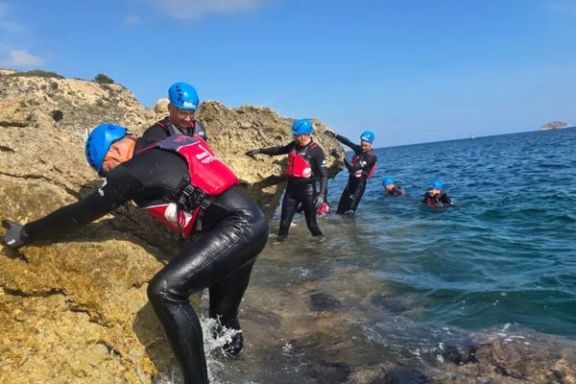 Participantes practicando coasteering entre las rocas y el mar en Alicante
