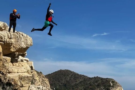 Participante saltando desde una roca al mar durante una ruta de coasteering