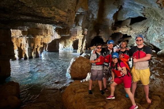Grupo posando en el interior de la Cova Tallada junto a una piscina natural