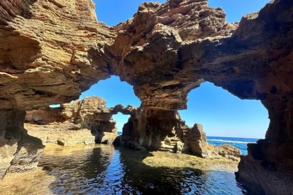 Formaciones rocosas y arcos naturales de la Cova Tallada vistos desde el mar