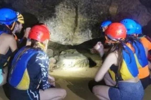 Participantes observando una antigua pila excavada en la piedra dentro de la Cova Tallada