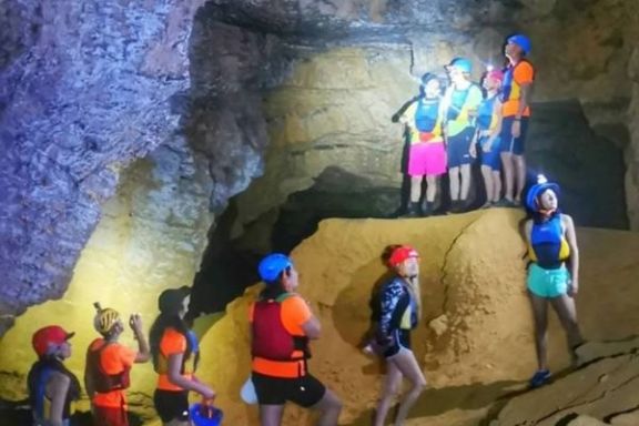 Grupo explorando el interior de la Cova Tallada con linternas frontales durante la visita guiada