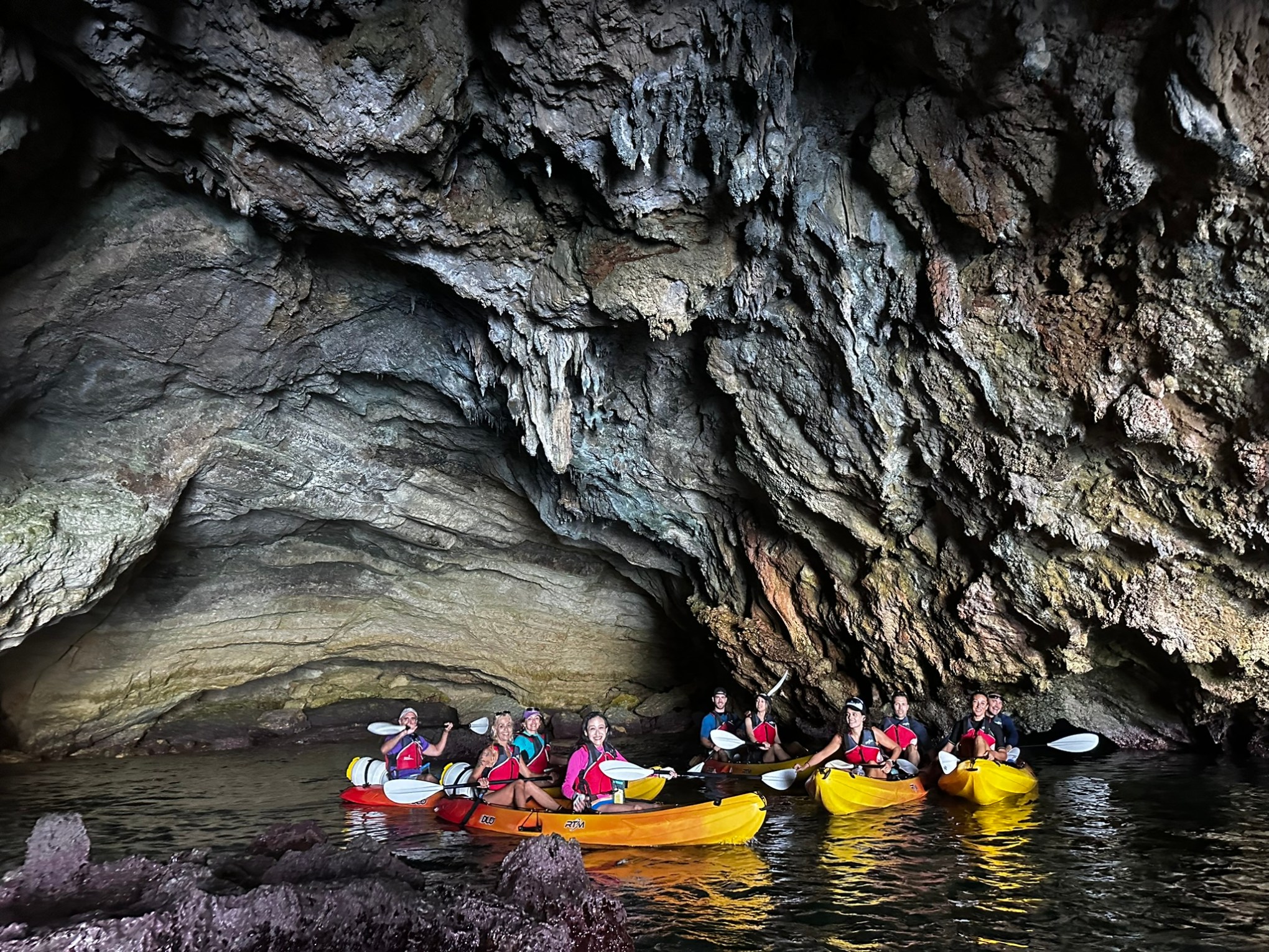 a group of people on a rock next to a body of water