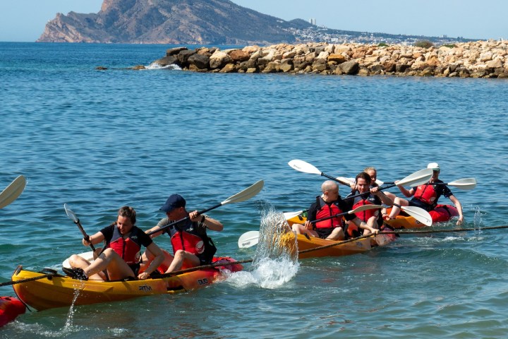 a group of people riding on the back of a boat in the water
