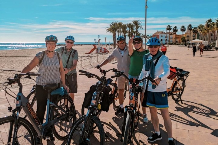 a group of people on a beach holding a bicycle