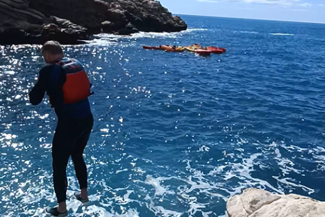 a man swimming in the water with a mountain in the background