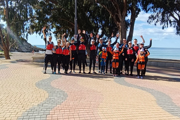 a group of people walking down a sidewalk next to a tree