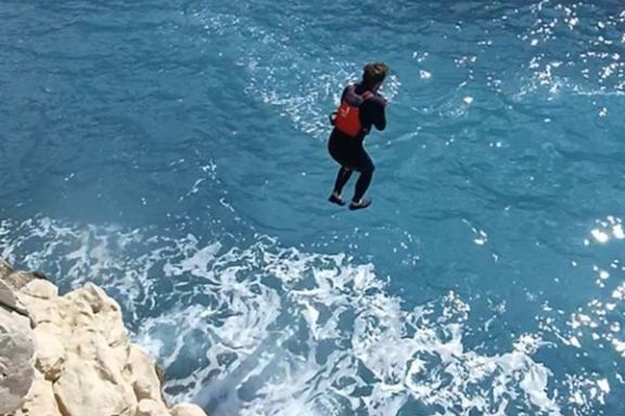 Participante realizando un salto al mar desde los acantilados durante la ruta en kayak