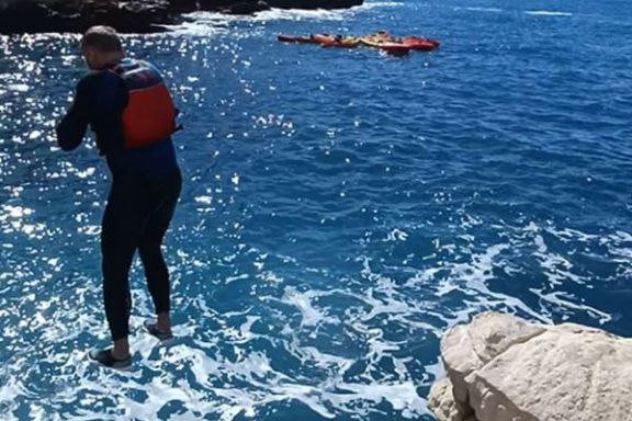 Participante saltando al mar desde las rocas durante la excursión en kayak