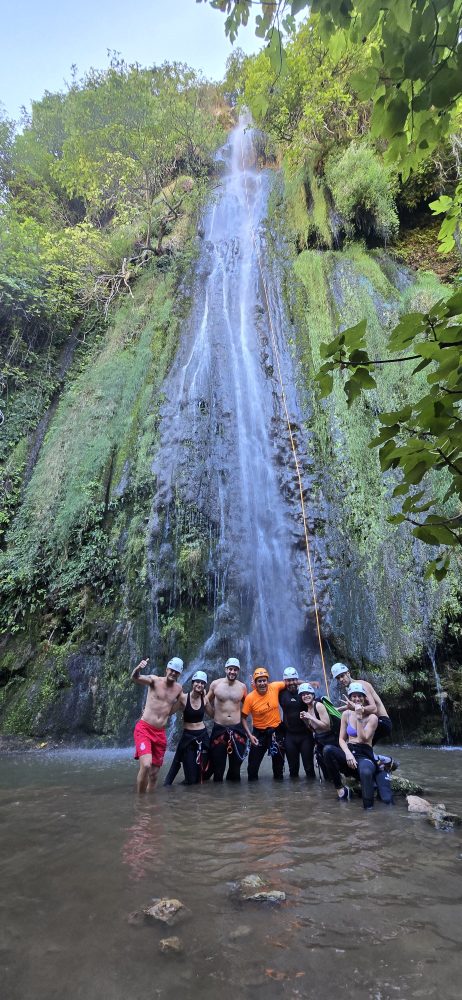 a group of people standing next to a waterfall