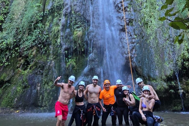 a group of people standing next to a waterfall