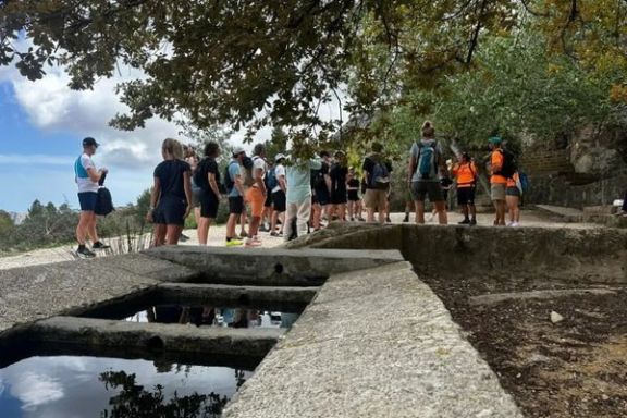 Senderistas haciendo una parada junto a una fuente durante una ruta por la montaña