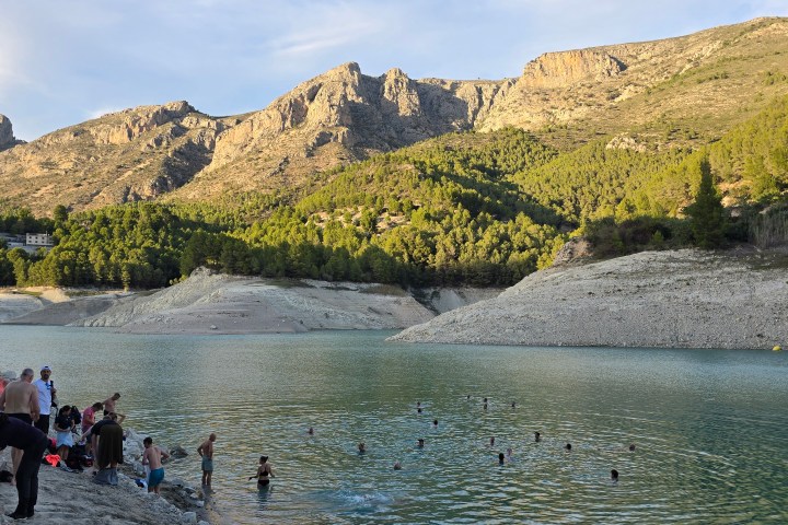 a group of people standing on top of a mountain lake
