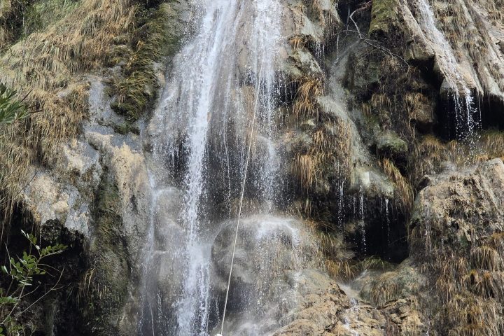 a waterfall with trees on the side of a snow covered slope