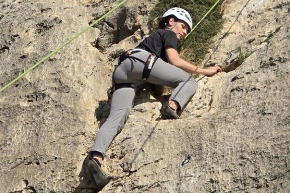 Participante practicando escalada en roca durante un bautismo de escalada en Elda, Alicante.