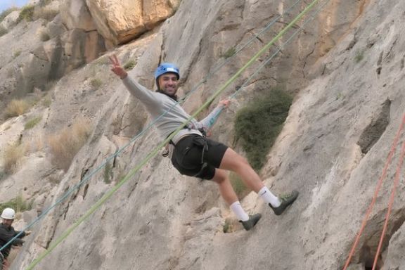 Participante sonriente suspendido con cuerdas durante una experiencia de escalada en Elda, Alicante.