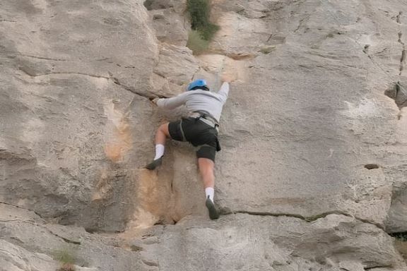 Participante aprendiendo técnicas de escalada en una pared natural de roca en Elda, Alicante.
