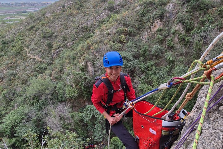 a man flying a kite on the side of a mountain