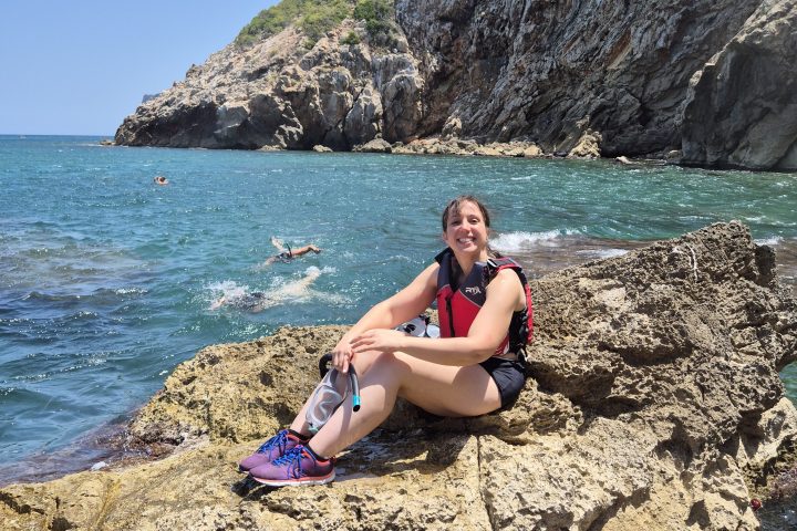 a woman sitting on a rocky beach