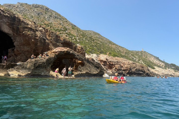 a group of people on a rock next to a body of water