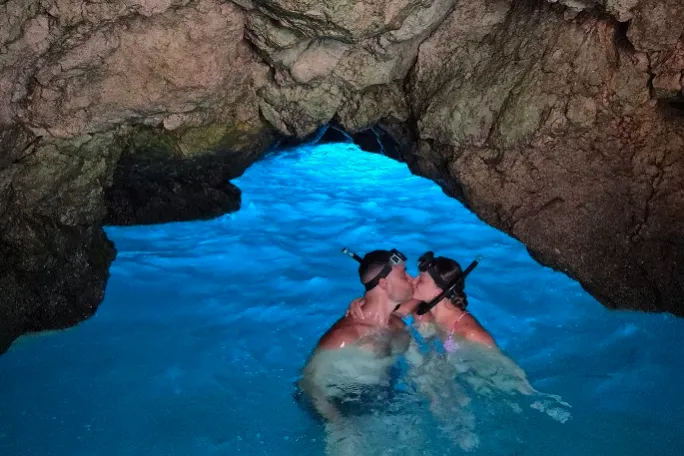 Couple kissing and snorkeling in a crystal blue water cave.