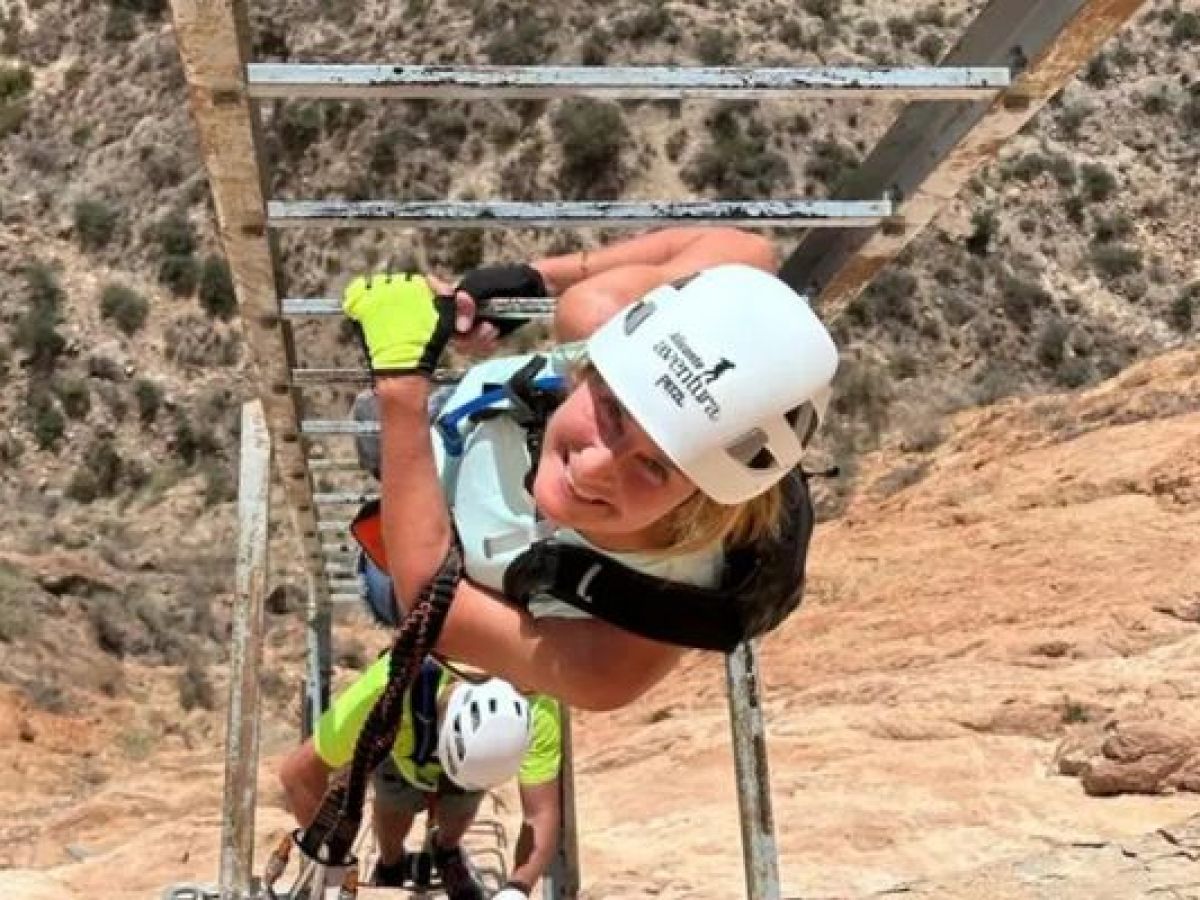 Participante ascendiendo una escalera metálica en una vía ferrata con Alicante Aventura