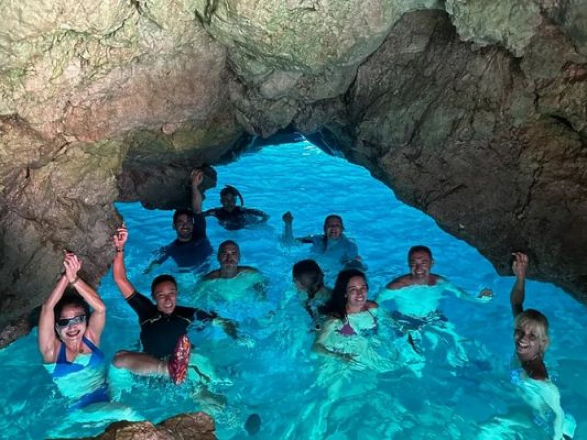 Grupo disfrutando de un baño en una cueva marina durante una ruta en kayak con Alicante Aventura