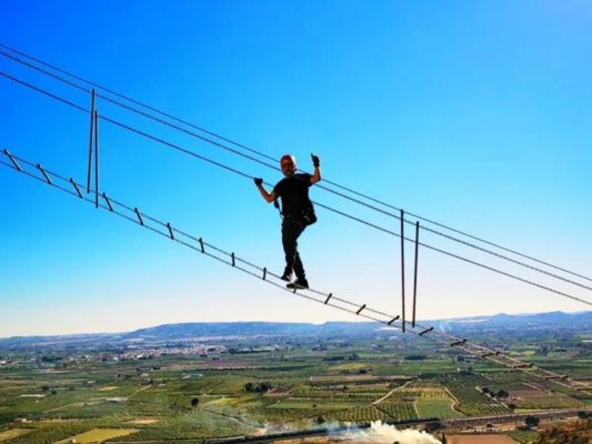 Participante cruzando un puente colgante en una vía ferrata con Alicante Aventura