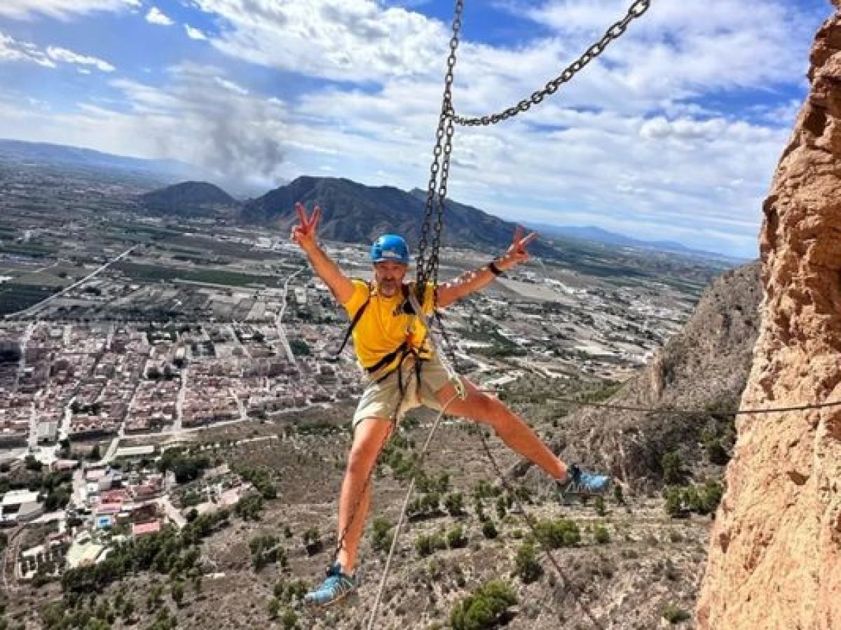 Participante cruzando un puente de cadenas durante una vía ferrata en Alicante